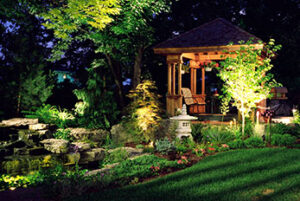 Beautiful garden with gazebo illuminated at night by landscape lighting